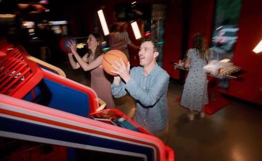 2_adults_playing_a_basketball_shooting_arcade_game.png